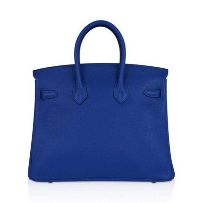 Vivid Saturated Cobalt Blue Pebble Grain Compact Trapezoid Hand Tote With Luminous Warm Golden Twist Lock Hardware And Matching Suspended Engraved Metal Padlock Charm